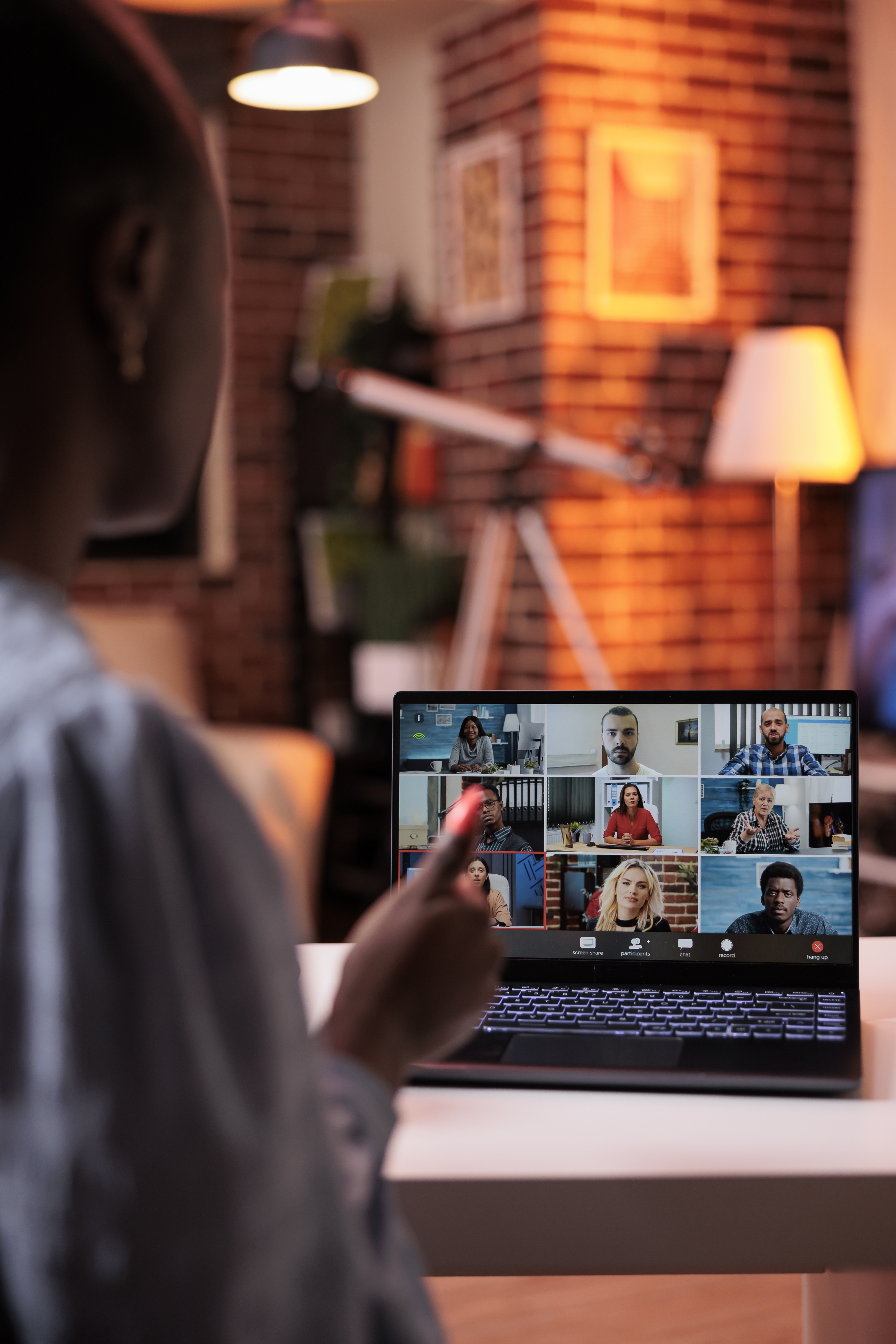 Businesswoman chatting with remote team on teleconference using laptop, back view.