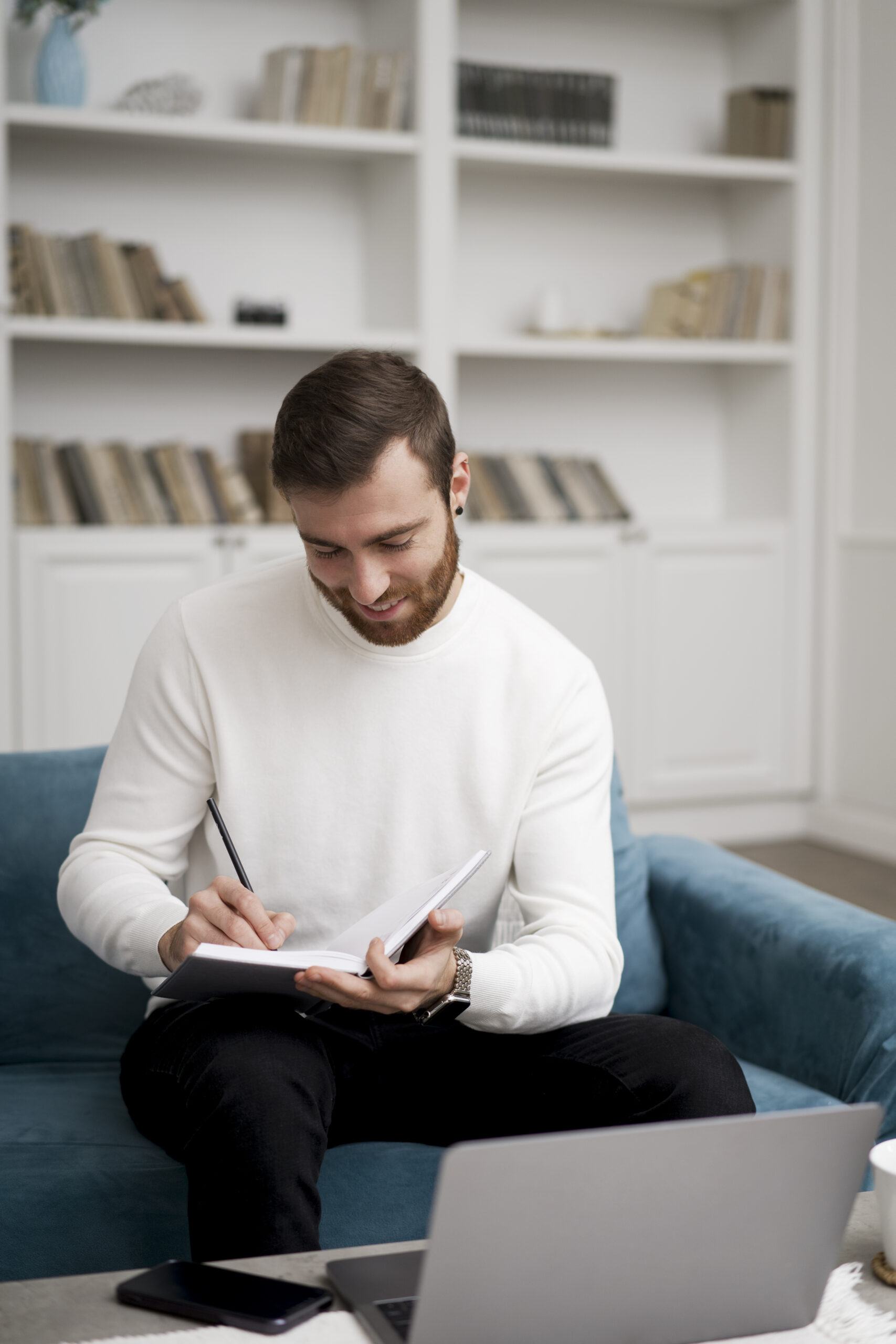 man e-learning, taking notes in a notebook in front of his laptop