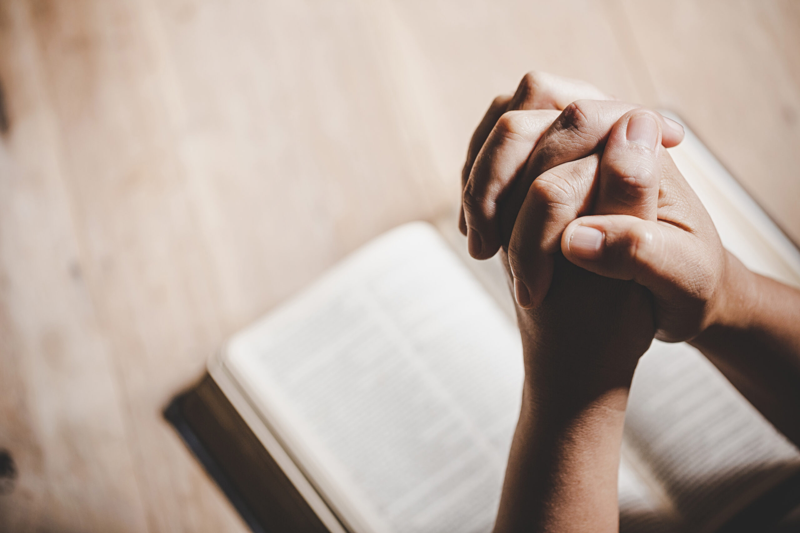 Spirituality and religion, Hands folded in prayer on a Holy Bibl Spirituality and religion, Hands folded in prayer on a Holy Bible in church concept for faith.